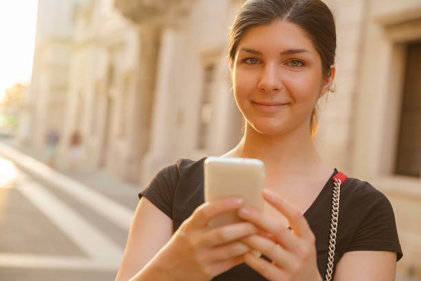 giovani donne holding con smartphone stili di vita casual scena urbana italia - ponytail brown hair tourist women foto e immagini stock