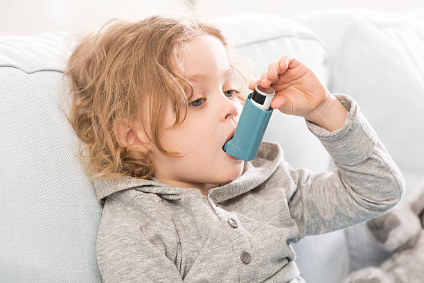 Small but conscious how to treat asthma Small child using his inhaler device for asthma respiratory disease stock pictures, royalty-free photos & images
