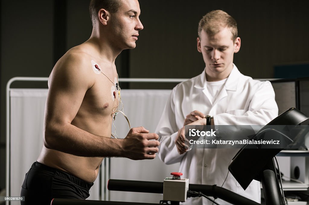 My sports career depends on my health Man running on treadmill during medical test and medic in white uniform Doctor Stock Photo