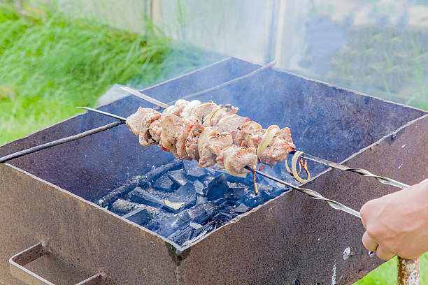en été pique-nique sur le gril sur la cuisson de la viande au charbon de bois. - unready photos et images de collection