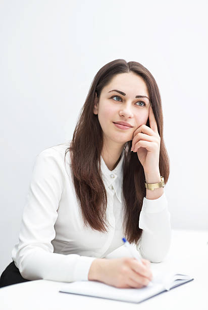 istock Young business woman thinking about plans and writes in diary 590285752