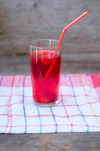 Glass of cherry juice or compote on wooden table with cherries