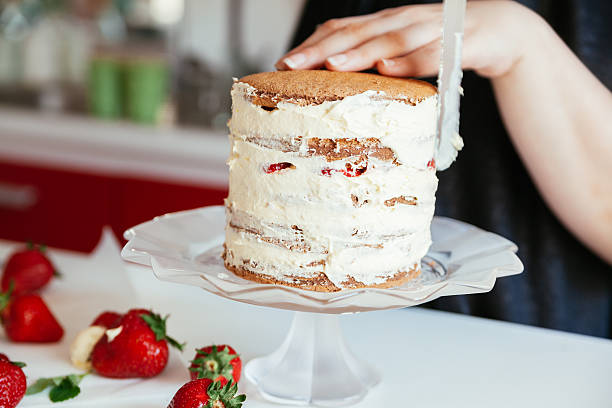 istock Woman Carefully Icing The Cake 590288140