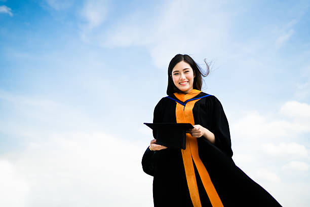Asian university graduate student woman smiling in graduation academic dress stock photo