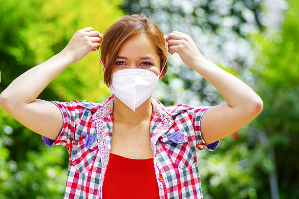 istock woman with colorfull clothes putting on a work mask 590298458