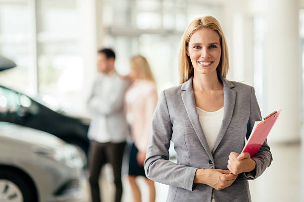 salesperson working at car dealership - verkoopster stockfoto's en -beelden