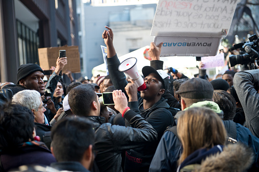 Chicago, Illinois, USA - December 9th 2015:  A Black Lives Matter protestor, surrounded by a crowd, during the Rahm resign protest. 