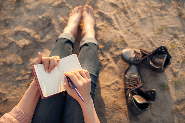 female makes notes and sitting on the beach; woman writes in diary and sitting on sand; poet stock pictures, royalty-free photos & images