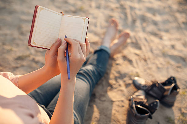 istock female makes notes and sitting on the beach; 590301748