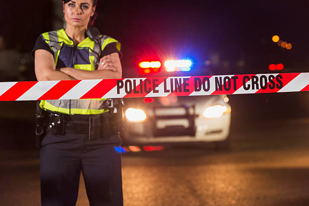 istock Policewoman standing behind crime scene tape 590301792