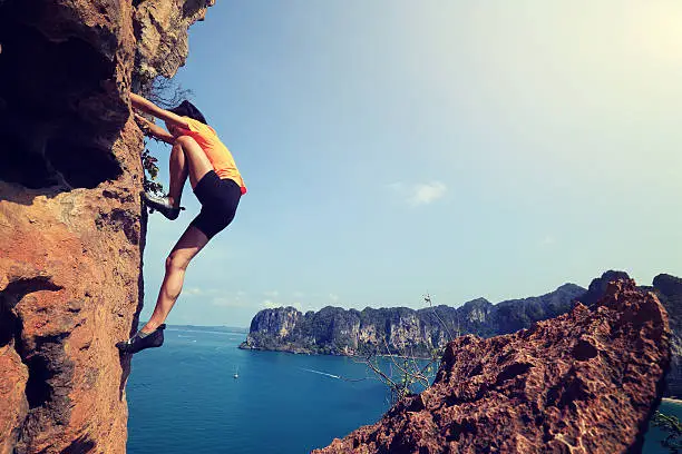 young woman rock climber climbing at seaside mountain rock