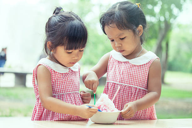 two little girls eat ice cream together two little girls eat ice cream together in vintage color tone asian little chinese girls eating ice cream stock pictures, royalty-free photos & images