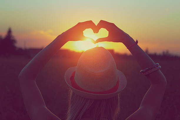 istock Girl making a heart-shape for the sunset. 590588990