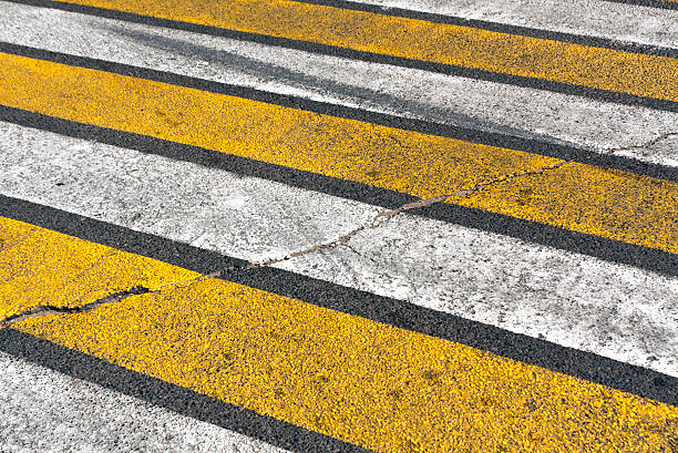 istock Old damaged white and yellow zebra pedestrian crossing. 590590118