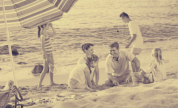 istock family with four kids relaxing on beach 590593414
