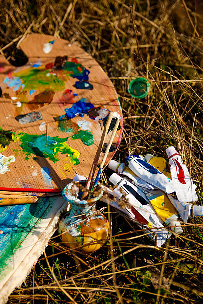 istock Palette with paints and brushes on picture on grass background 590601028