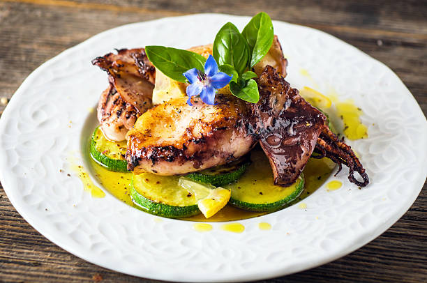 istock Grilled squid with lemon and zucchini on wooden background 590604936