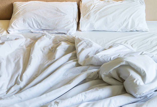 istock Messy white bed sheets and white pillows in the morning 590604980