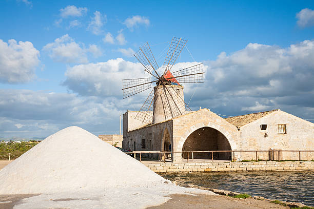 Salt pan windmill A salt pan windmill and heap of sea salt near Trapani in western Sicily, italy salt flat stock pictures, royalty-free photos & images
