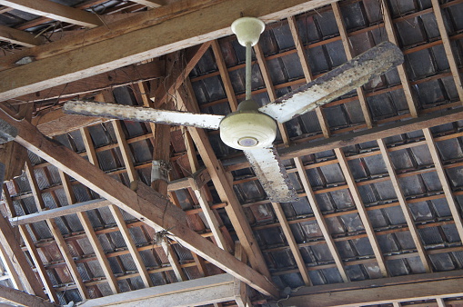 Ceiling fan hung under wooden roof.
