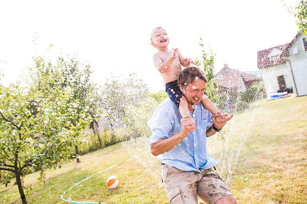 スプリンクラーで彼の父親と一緒に小さな男の子, 夏 - child balloon outdoors little boys ストックフォトと画像