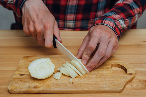 istock Man hands slicing fresh onnion by ceramic knife 590609742