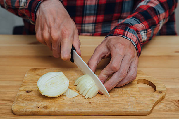 istock Man hands slicing fresh onnion by ceramic knife 590609914