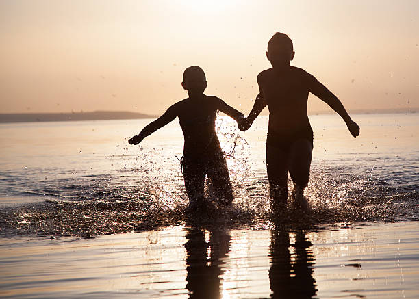 istock Children run along the water at sunset 590611528