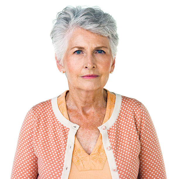 Portrait of confident senior woman standing hands clasped over white background.