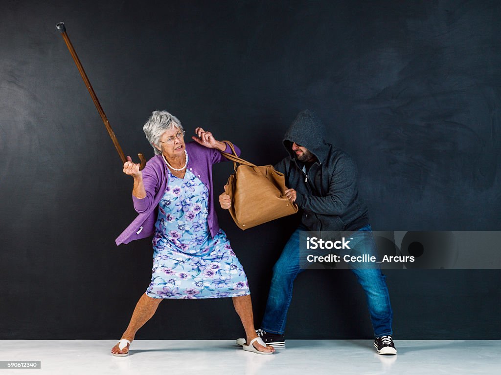Get your hands off my bag! Studio shot of an elderly woman having her handbag stolen by a thief against a gray background Stealing - Crime Stock Photo