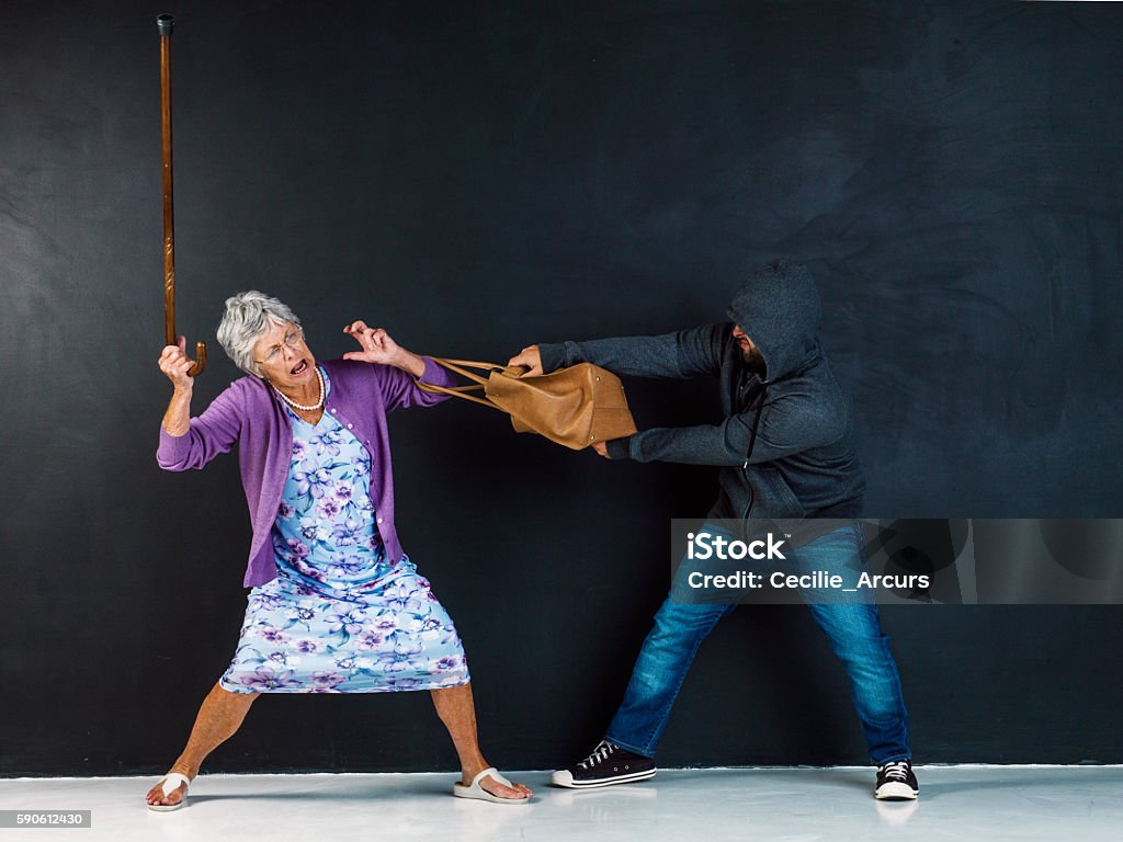Somebody call the police! Studio shot of an elderly woman having her handbag stolen by a thief against a gray background Stealing - Crime Stock Photo