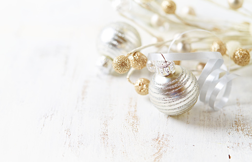 Silver and golden Christmas ornaments on a white wooden background