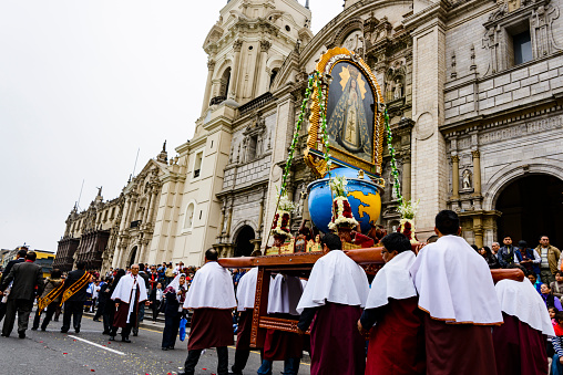 Lima, Peru - June 12, 2016: Religious celebration in front of the Lima Cathedral.  Large crowds of people are gathered to watch a procession with tranditional folkloric dancers and religious artifacts and floats.