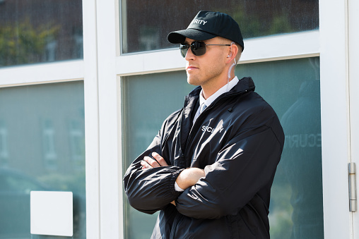 Young Male Security Guard Standing At The Entrance