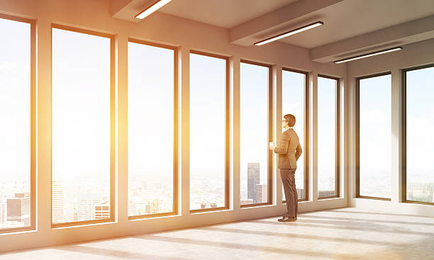 istock Businessman in empty room watching at city 590615138