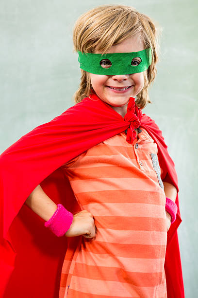 istock Smiling boy dressed as superhero in classroom 590617740