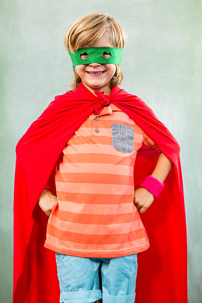 istock Boy dressed as superhero standing in classroom 590617804