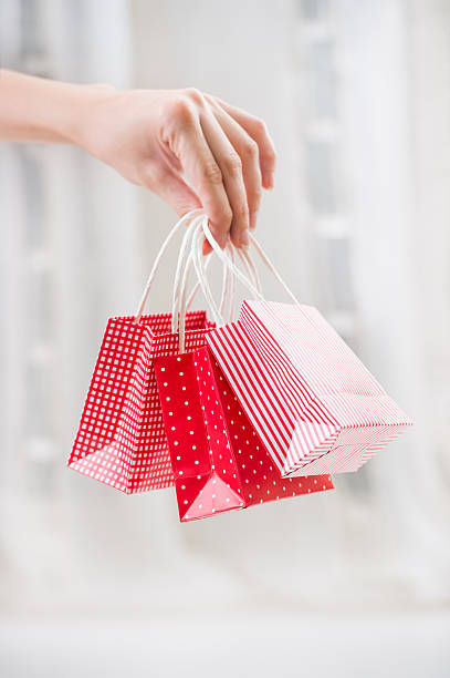 istock Female hand holding red gift bag with presents 590618900