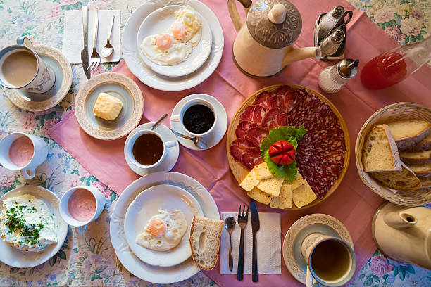 Traditional farmers breakfast for two on table at Solcava panoramic road in Slovenia. There are all local products like eggs, milk, butter, cottage cheese, tea, coffee, bread, ham, yogurt and jam.
