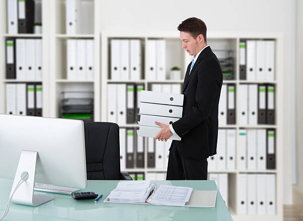 istock Businessman Carrying Binders By Desk 590621686