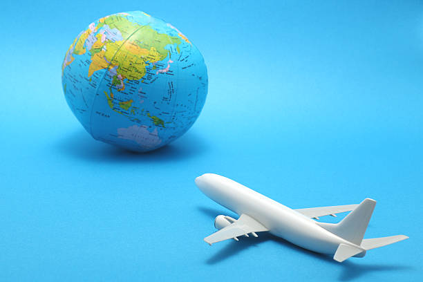 istock Miniature toy airplane and globe on blue background. 590625378