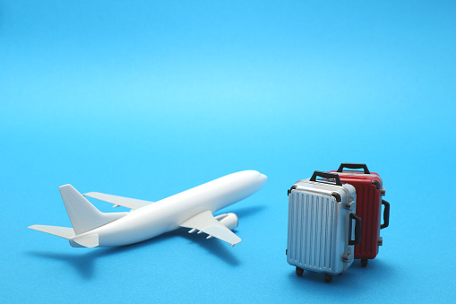 Miniature toy airplane and suitcases on blue background.