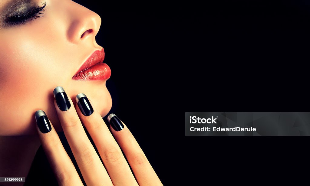 French-style manicure on nails and red lipstick. Beautiful model brunette shows black and silver French-style manicure on nails and red lipstick.Luxury fashion style manicure and makeup . Fingernail Stock Photo