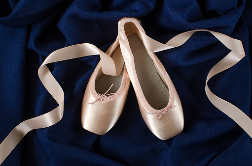 A pair of pointe shoes on blue background