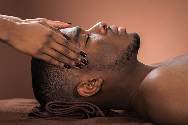 Man Receiving Forehead Massage Young African Man Receiving Forehead Massage In Spa black male massage stock pictures, royalty-free photos & images