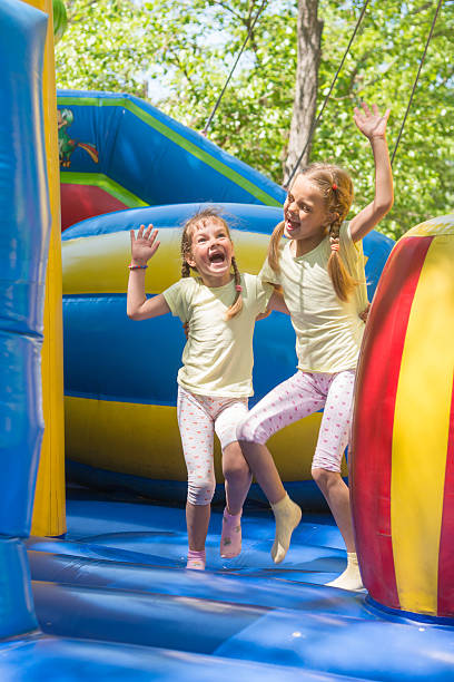 istock Two girls grimacing happily jumping on an inflatable trampoline 591407720