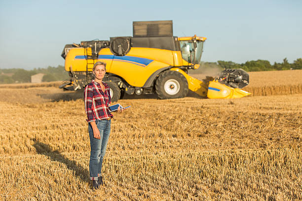 istock female farmer and combine harvester 591408552