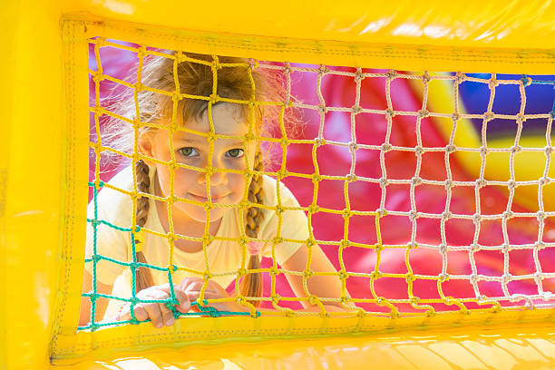 istock five-year girl is looking through a mesh trampoline inflatable 591408740