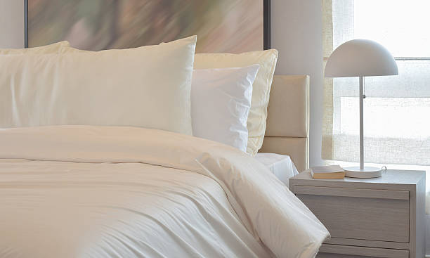 istock Cozy bedroom with white pillows and reading lamp 591408804