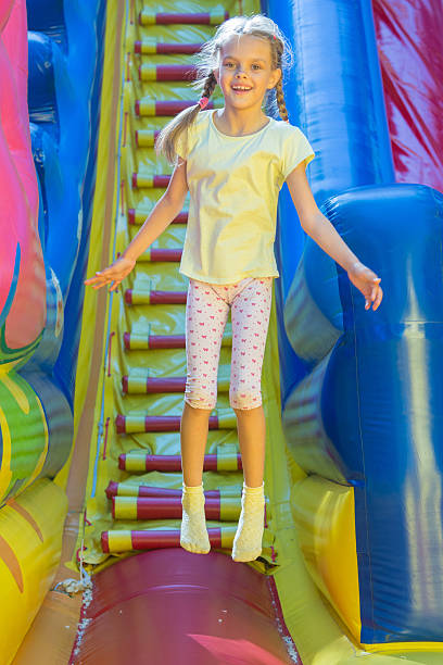 istock Happy girl jumping on an inflatable trampoline 591409070